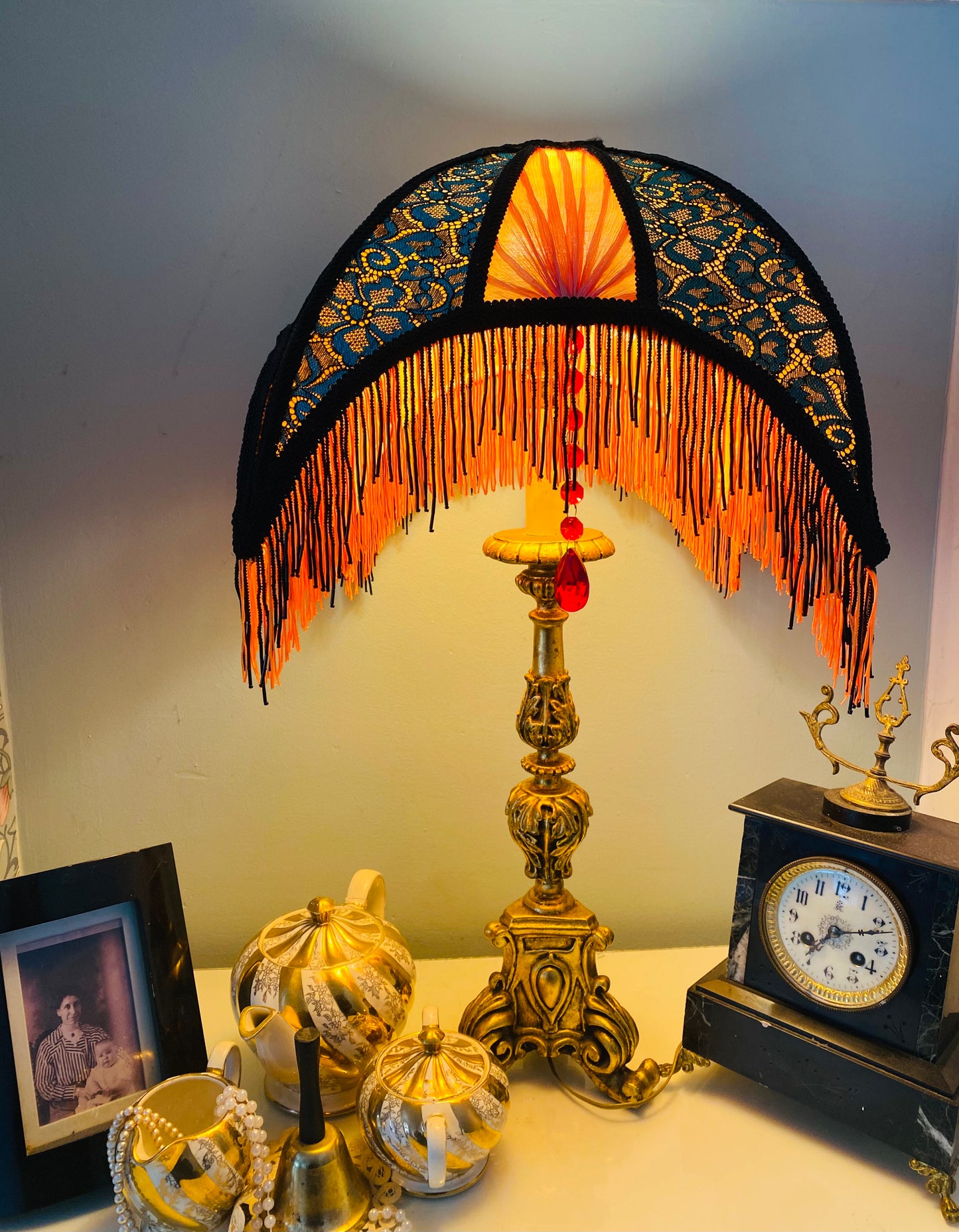 front view of lace panel – “Intricate green and black lace panel over orange silk on an Art Deco crescent lampshade – elegant handcrafted detail with a sunset-inspired palette.”