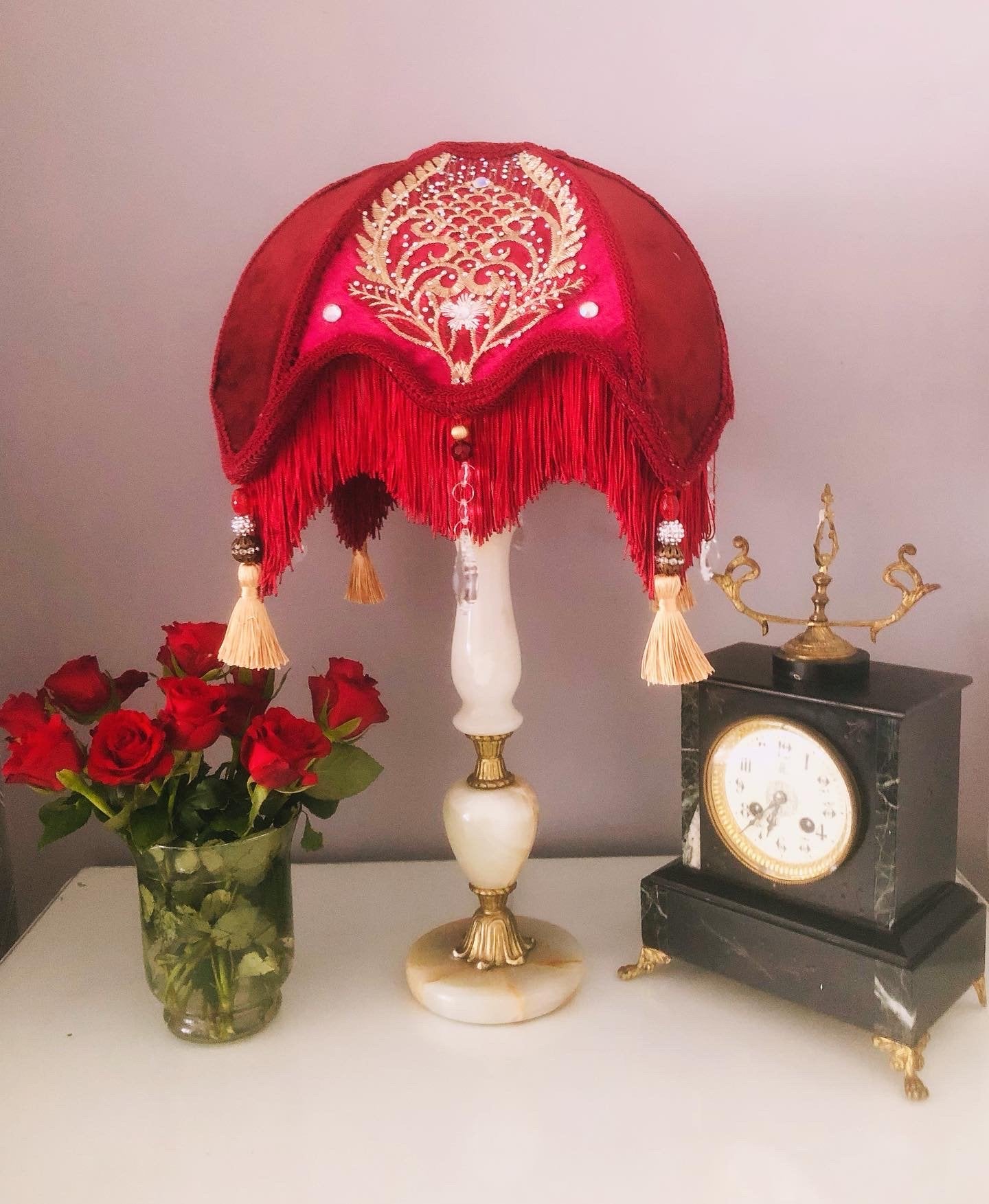 Close-up of fringe and tassels – “Gold tassels and ruby red diamante jewels decorating the edge of a red Victorian lampshade – vintage-inspired luxury lighting accent.”