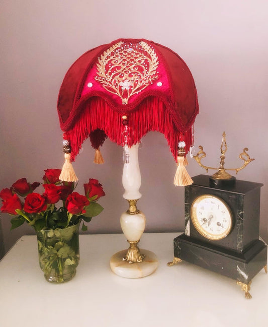 Close-up of fringe and tassels – “Gold tassels and ruby red diamante jewels decorating the edge of a red Victorian lampshade – vintage-inspired luxury lighting accent.”