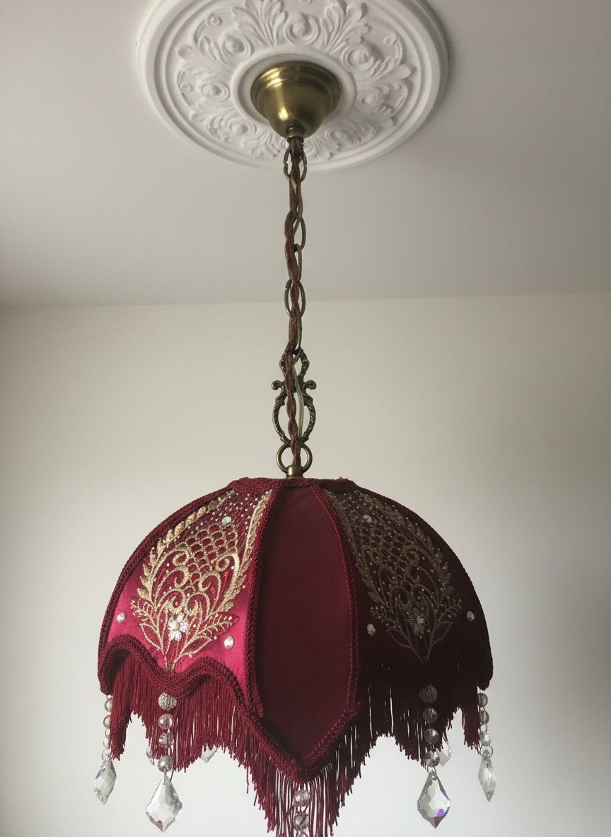 Close-up of  red velvet and gold chiffon embroidery on a Victorian lampshade – elegant handmade textile detail.”