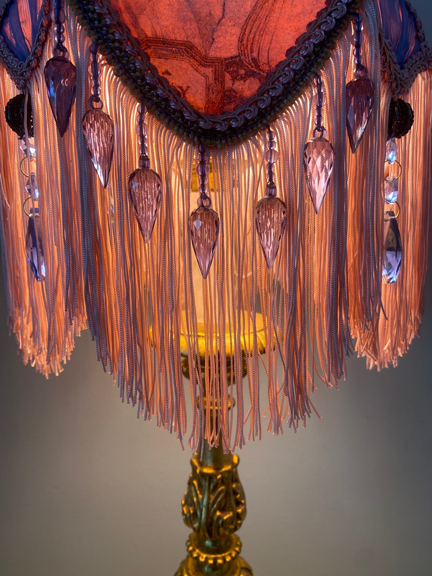 Close-up of fringe detail – “Soft pink fringe and blue glass beaded trim cascading from the edge of a Victorian tulip lampshade – antique-inspired vintage lighting accent.”
