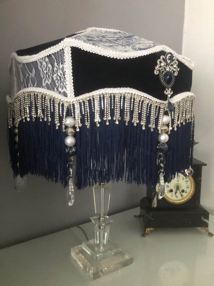 Decorative Victorian lampshade with blue velvet toile and lace panels and dark blue fringes. with glass crystal tassel and diamonte trim, slight side view 